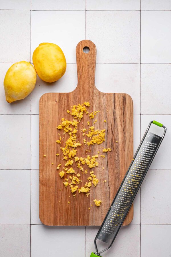 lemon zest and a microplane grater on a cutting board.