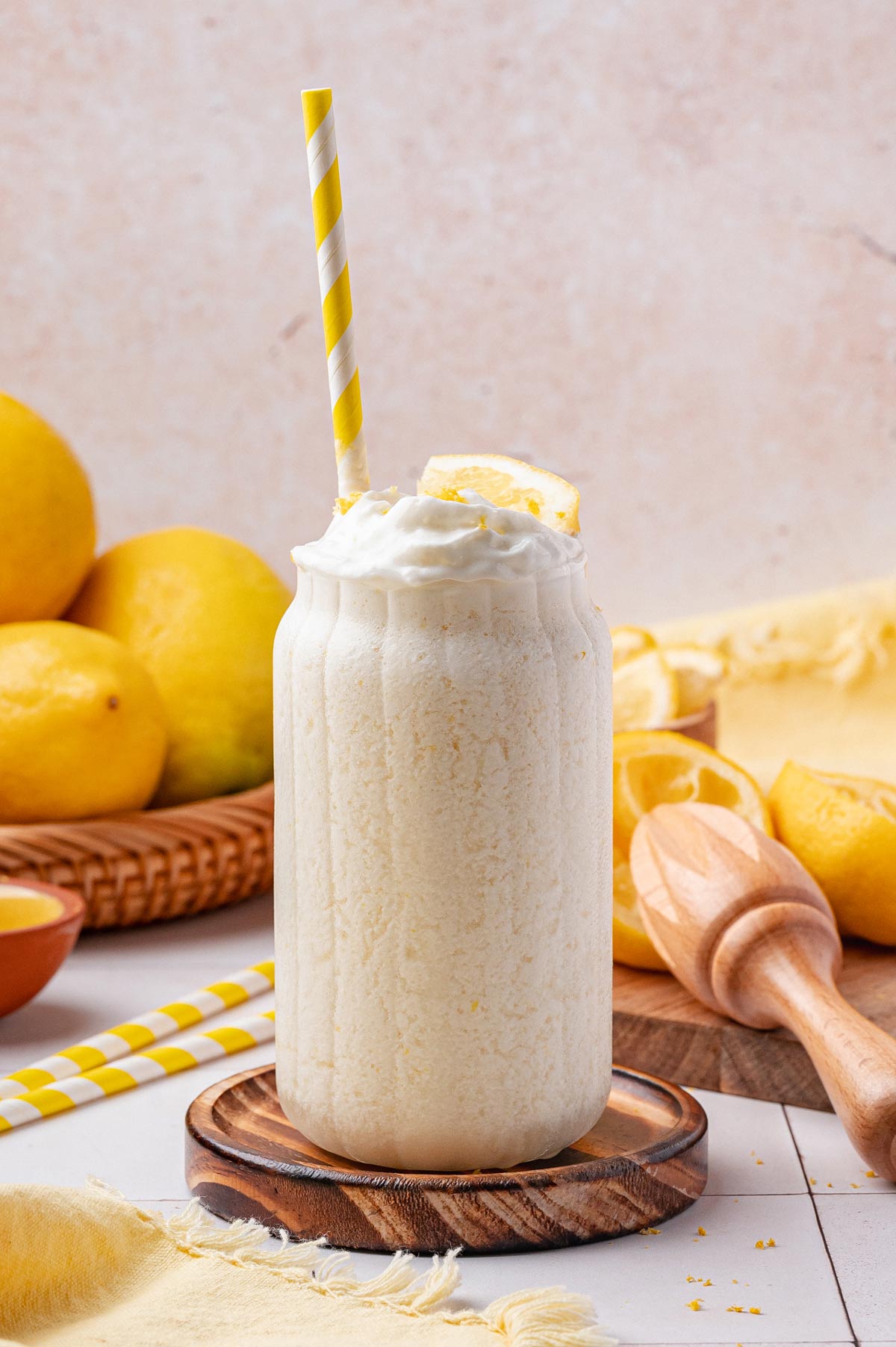 tall glass of creamy frozen lemonade with a yellow striped straw.