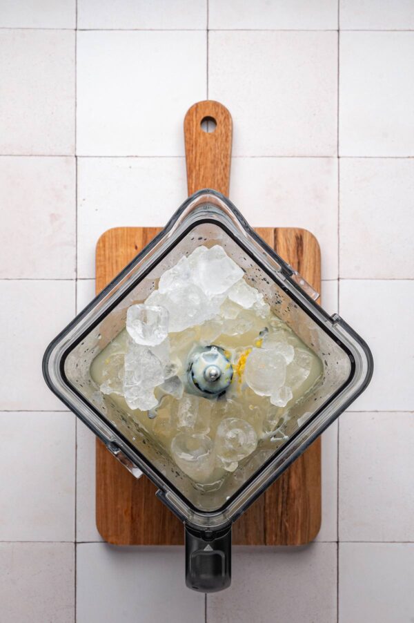 overhead view of a blender filled with lemon juice, sweetened condensed milk, and ice.
