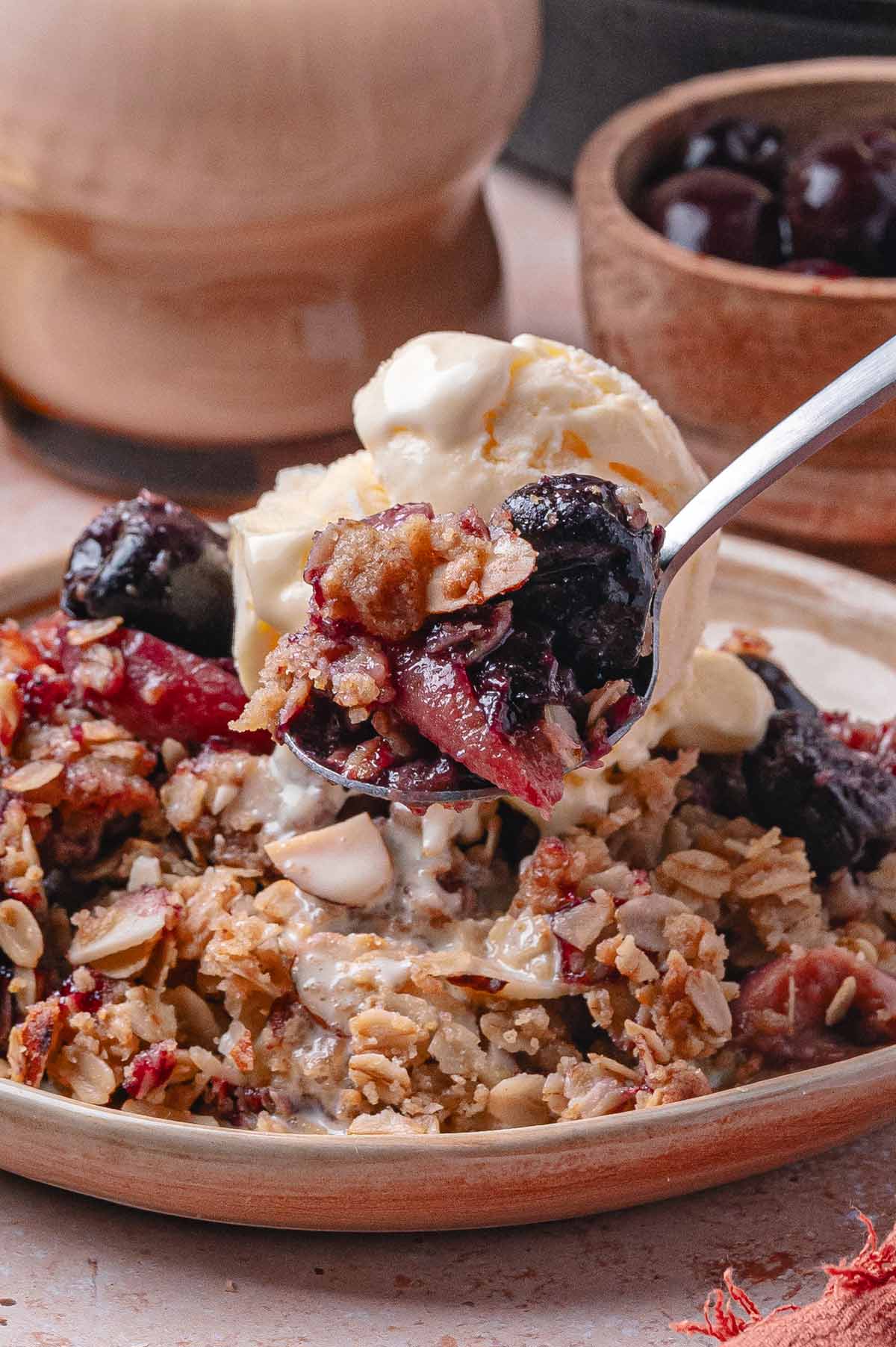 close up view of a spoon scooping up peach crisp.