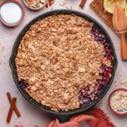 peach cherry crisp with a crunchy oat topping in a cast iron skillet.