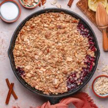 peach cherry crisp with a crunchy oat topping in a cast iron skillet.