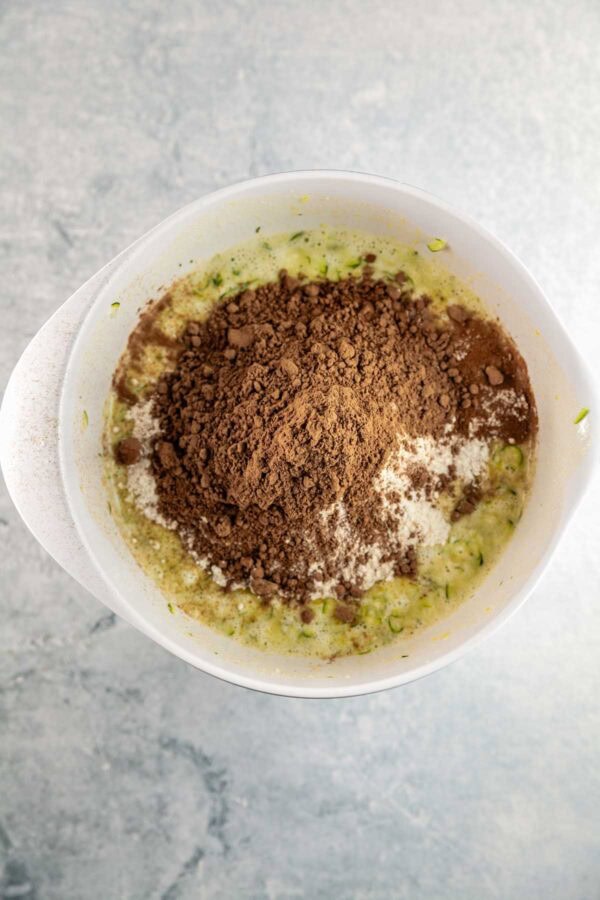 adding dry ingredients to the wet ingredients for zucchini bread.