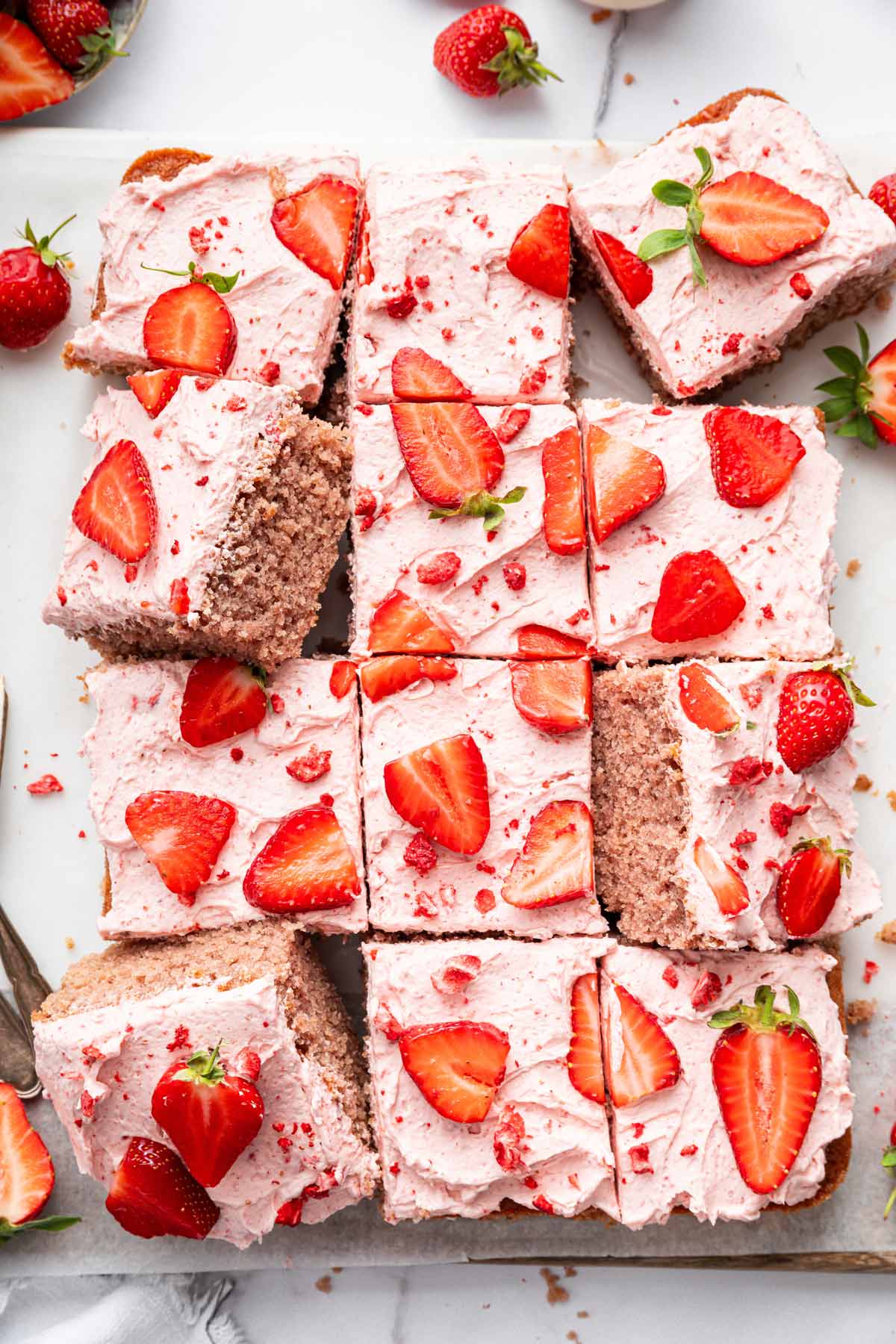 strawberry sheet cake with strawberry cream frosting decorated with sliced strawberries.