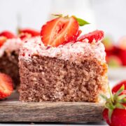 slice of strawberry sheet cake topped with fluffy strawberry buttercream and fresh strawberry slices.