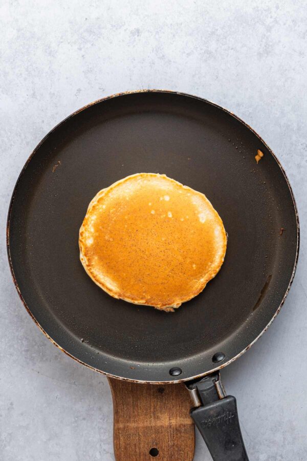 golden brown pancake cooking in a skillet.
