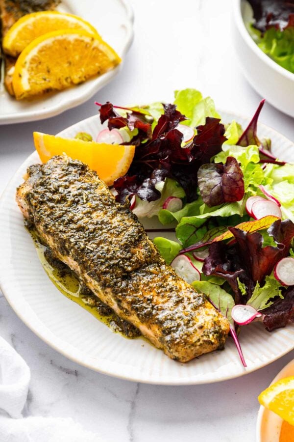 herb covered roasted salmon next to a salad.