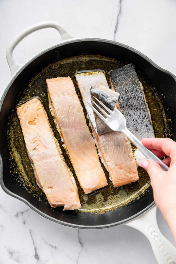 using a fork to peel skin off salmon.