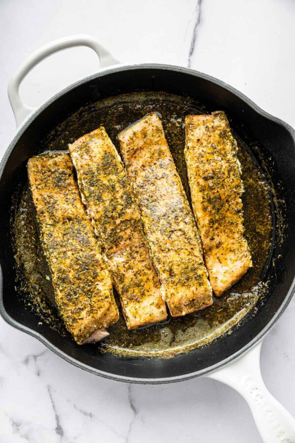 flipping salmon cooked in butter and herbs.