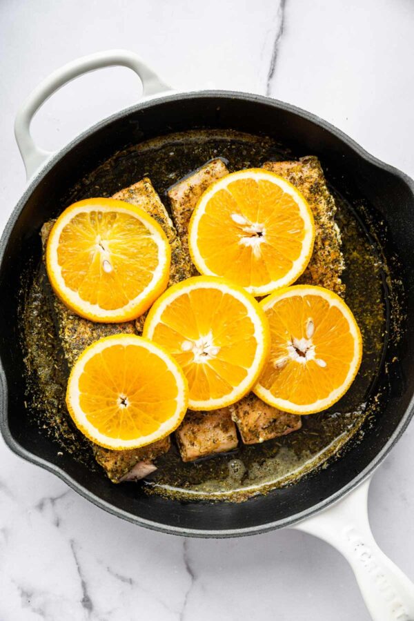 topping salmon with thinly sliced orange rounds.
