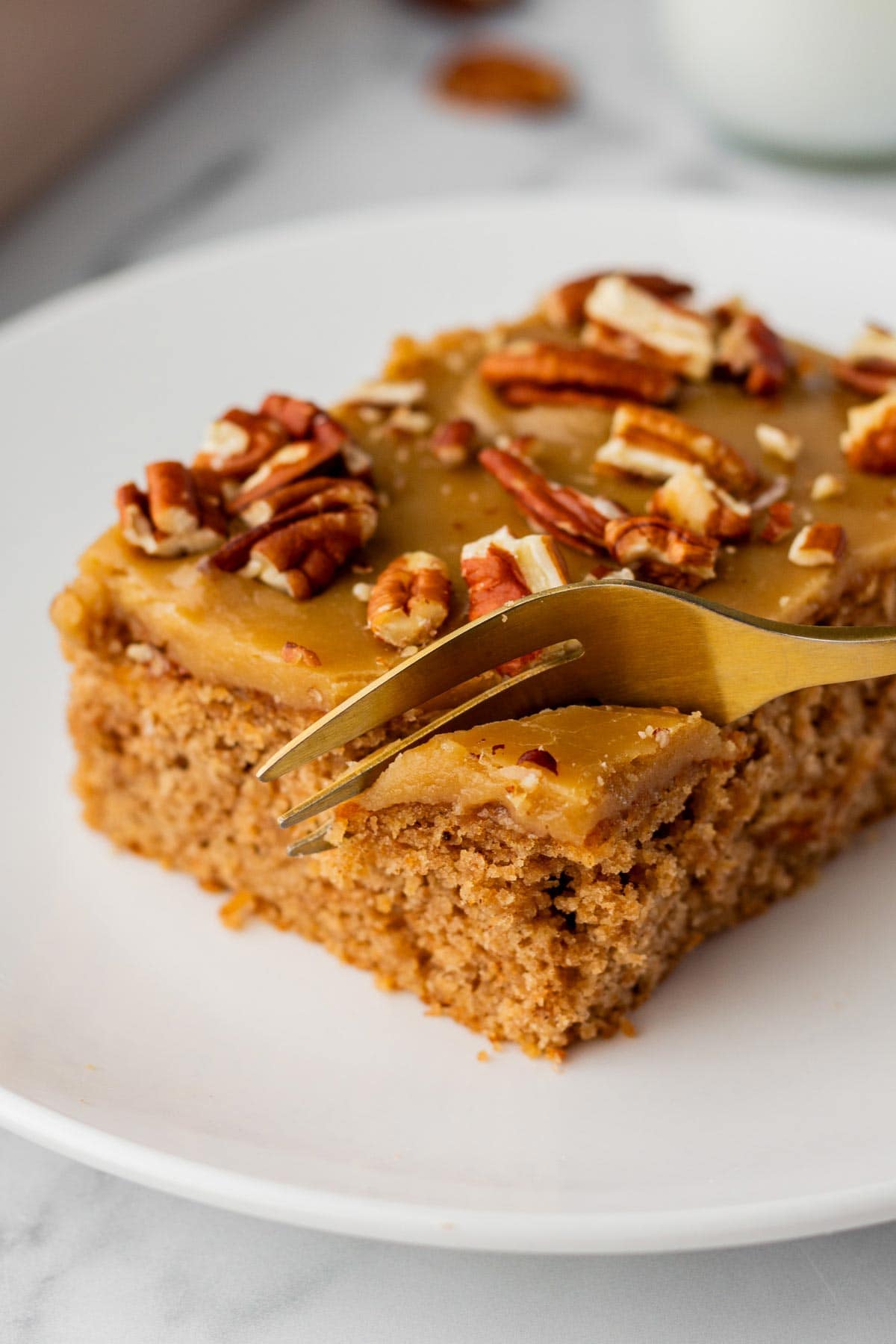 fork digging into a slice of cake with a brown sugar glaze.