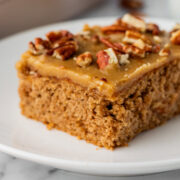 side view of a slice of applesauce spice cake covered with brown sugar icing.