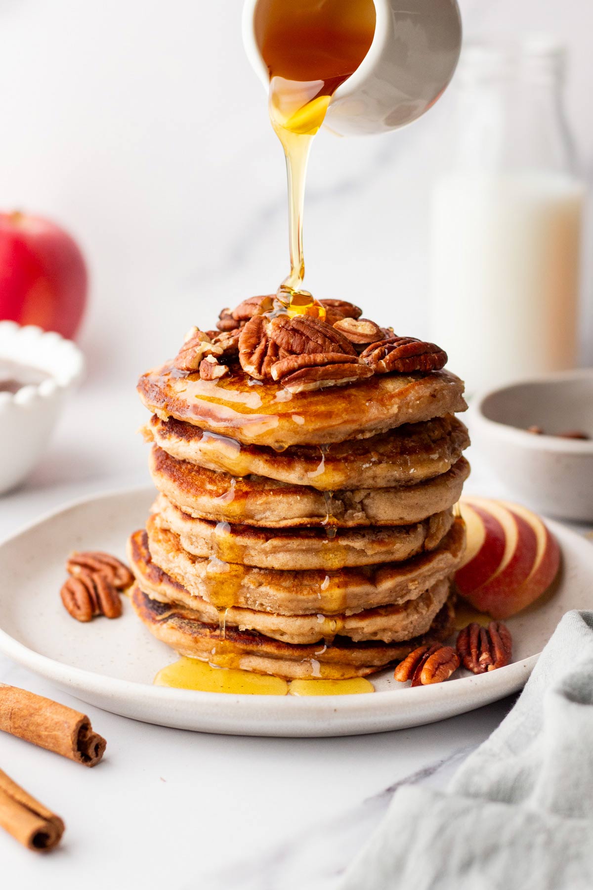 stack of fluffy apple butter pancakes with maple syrup pouring down the sides.