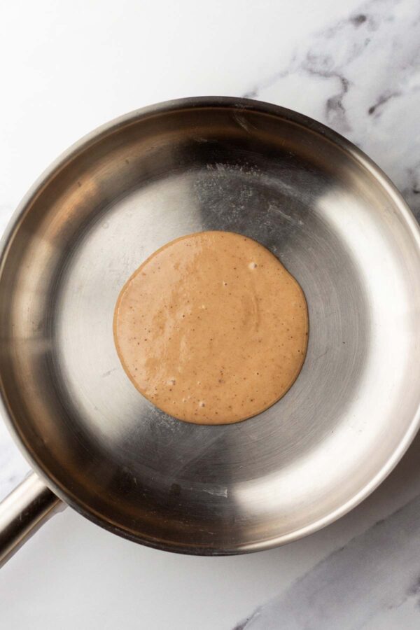 cooking pancakes in a skillet with bubbles forming on the surface.