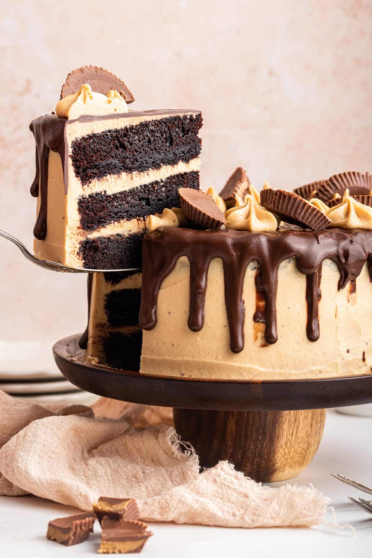 cake server lifting up one slice of a three layer chocolate peanut butter cake.