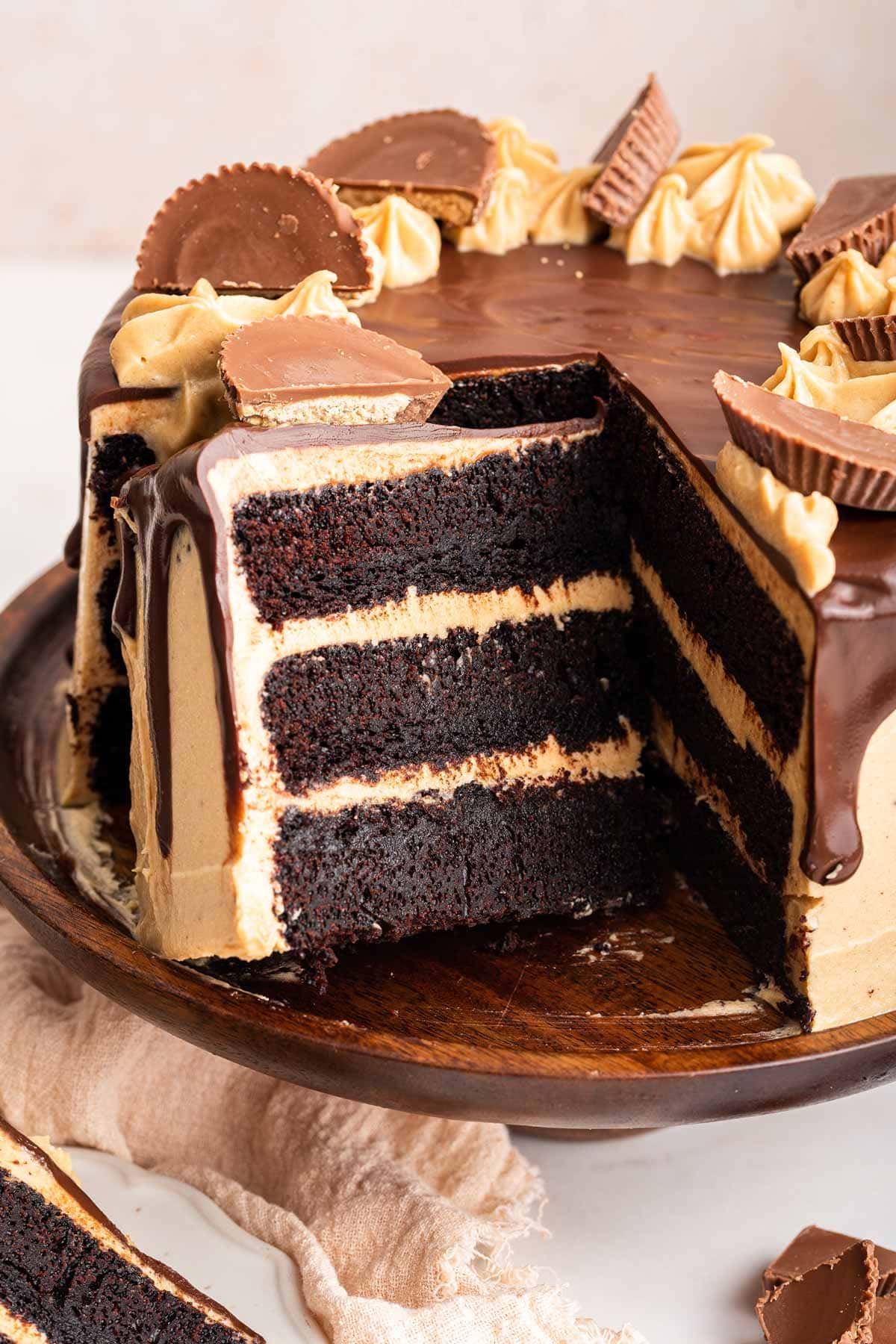 three layers of chocolate cake with peanut butter frosting covered in smooth chocolate ganache.