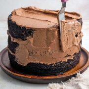spreading nutella buttercream frosting on a chocolate layer cake.