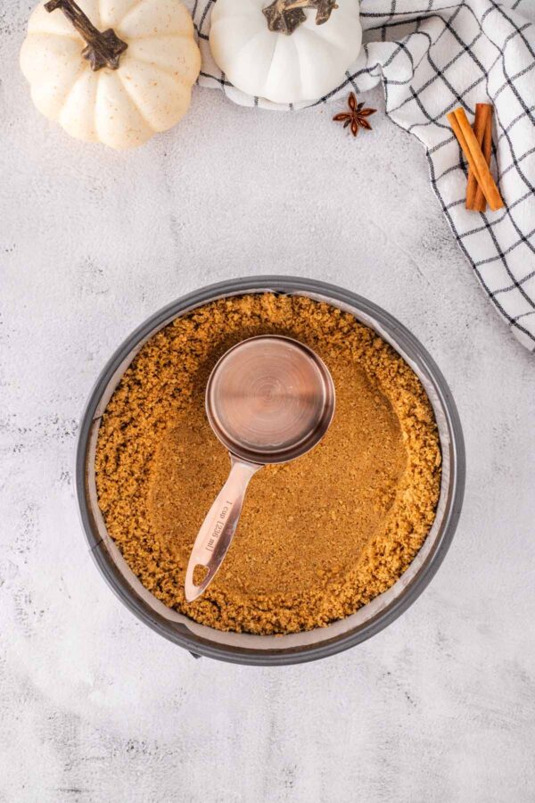pressing a graham cracker crust into a springform pan.