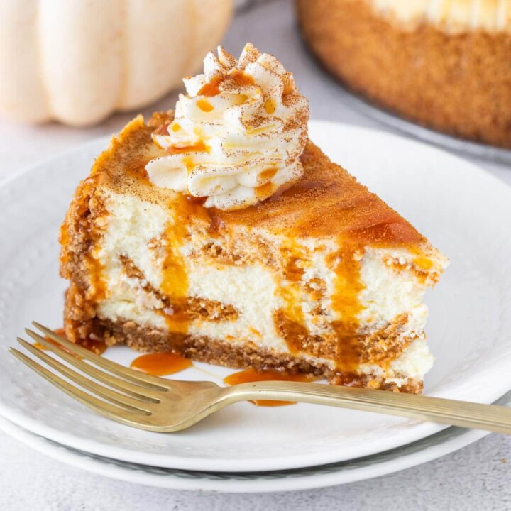 slice of pumpkin swirl cheesecake with caramel sauce and whipped cream.