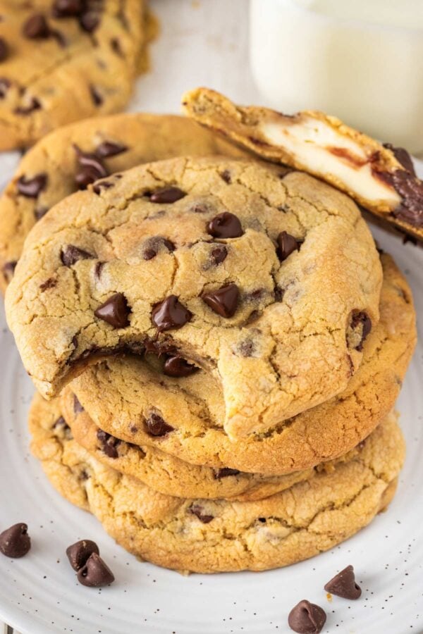 stack of cheesecake stuffed chocolate chip cookies with a bite taken out of one.