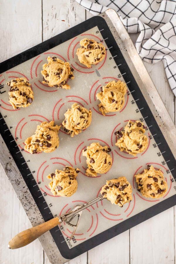 large scoops of cookie dough on a silicone baking mat.