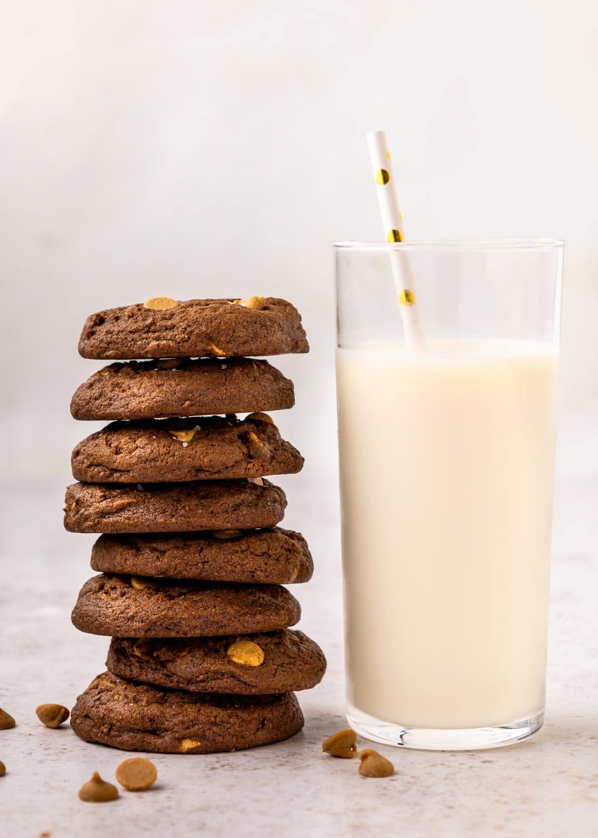 vertical stack of chocolate cookies next to a glass of milk.