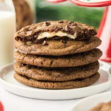 stack of chocolate cookies with one cut open to show the cheesecake center.