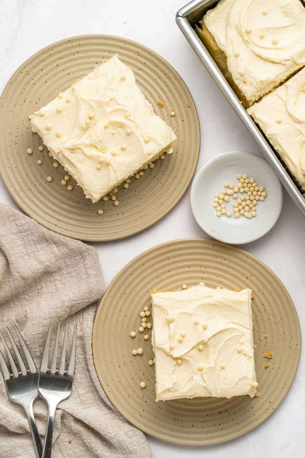 two slices of vanilla sheet cake on dessert plates.