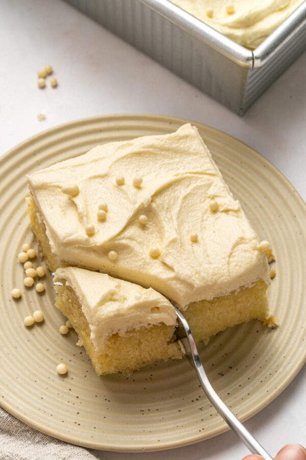 fork cutting into one square of a vanilla sheet cake.