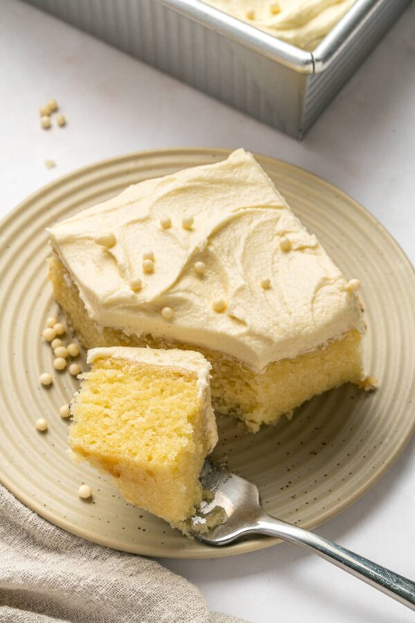forkful of vanilla sheet cake on a dessert plate.