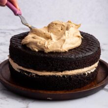 spreading a thick layer of caramel frosting on a cake.