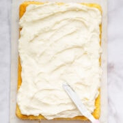 spreading coconut cream cheese frosting on a sheet cake.