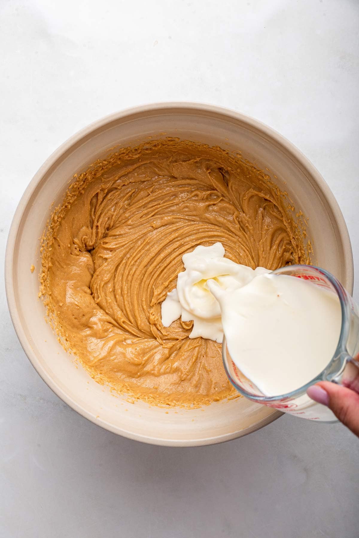 adding heavy cream to peanut butter frosting.