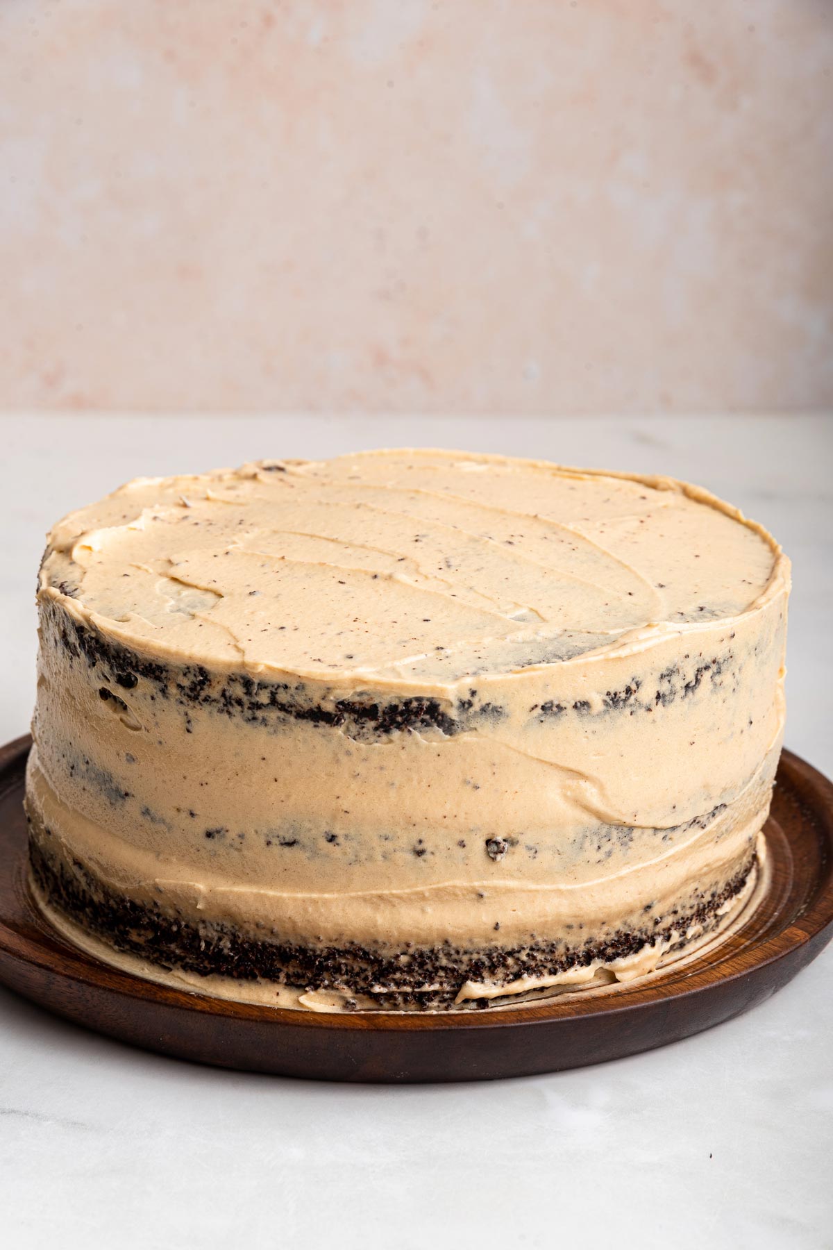 crumb coat of peanut butter frosting on a chocolate layer cake.