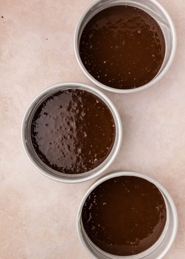 chocolate cake batter divided into three cake pans.