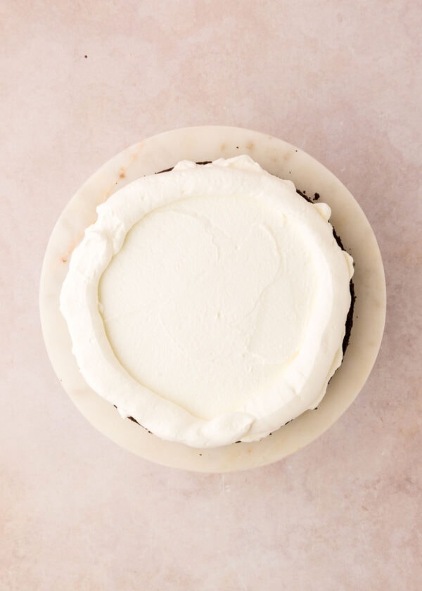 spreading whipped cream on a layer of chocolate cake.