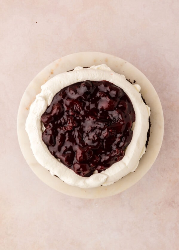 filling a cake layer with homemade cherry filling.