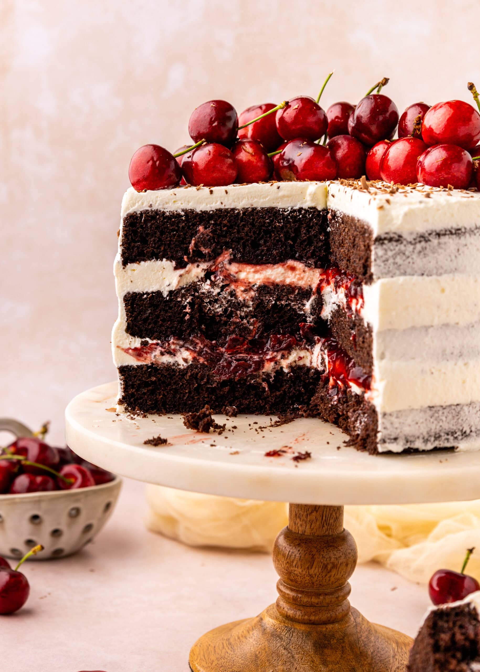 black forest cake with two slices removed showing the layers of whipped cream and cherries inside.
