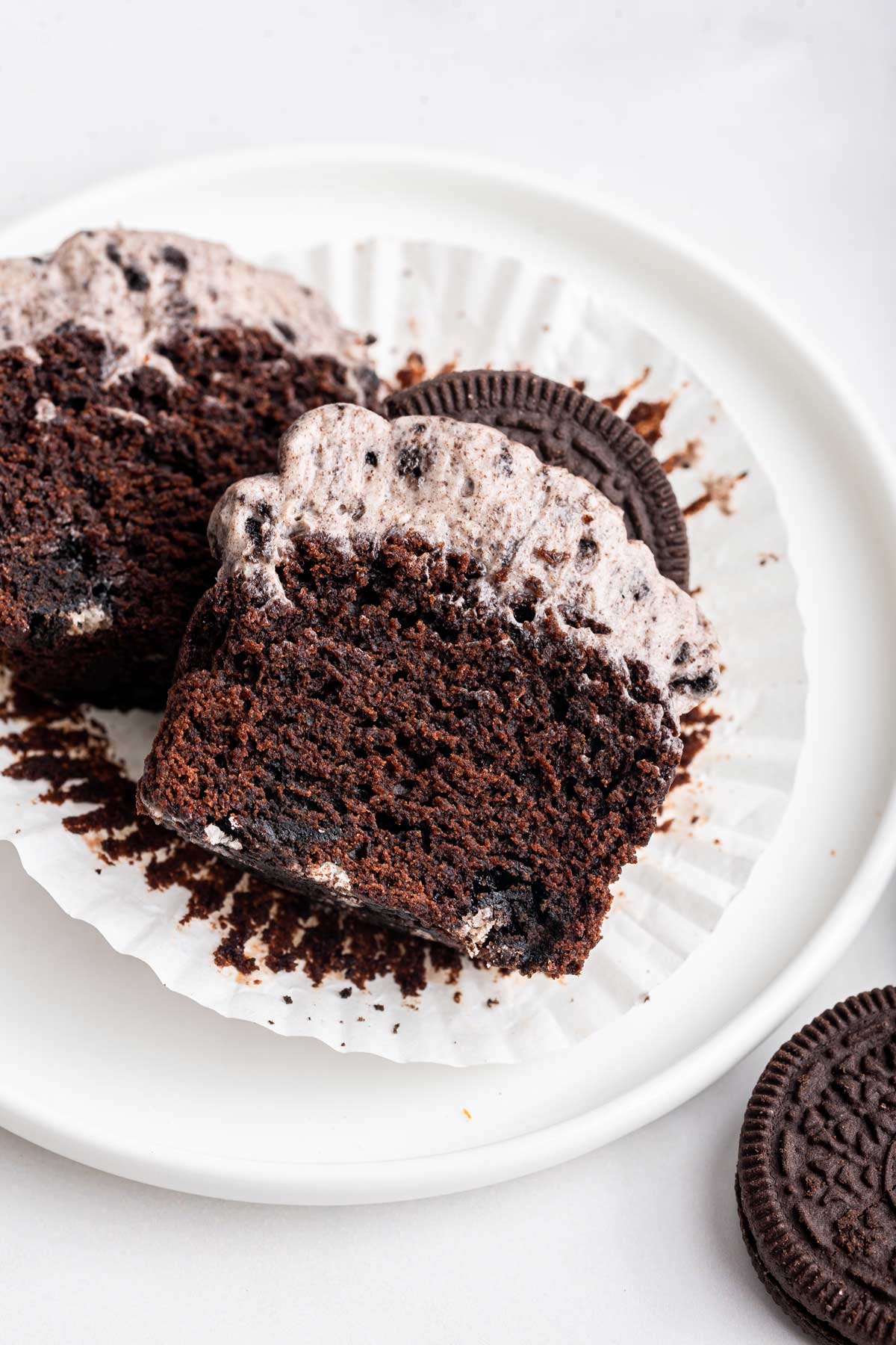 Oreo cupcake sliced in half showing a thick pile of frosting on top.