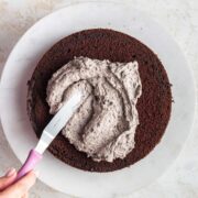 spreading Oreo frosting on a layer of chocolate cake.
