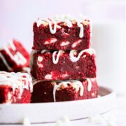 three red velvet brownies stacked on a white plate.