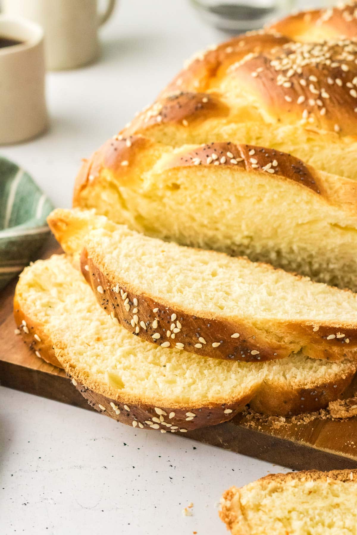 loaf of challah on a cutting board with several pieces sliced.
