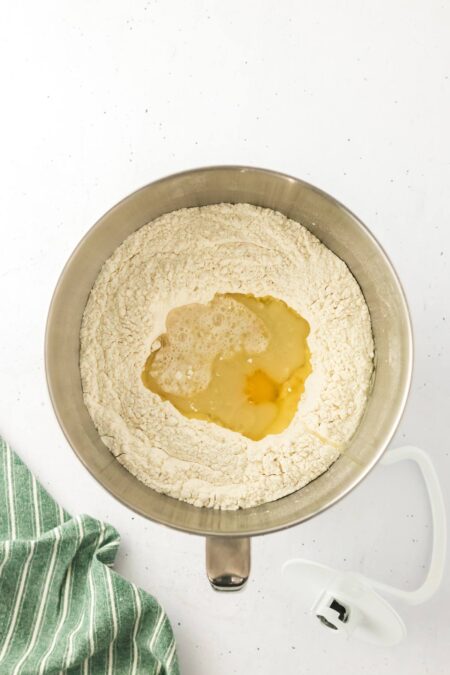 adding oil and water to flour to make challah dough.