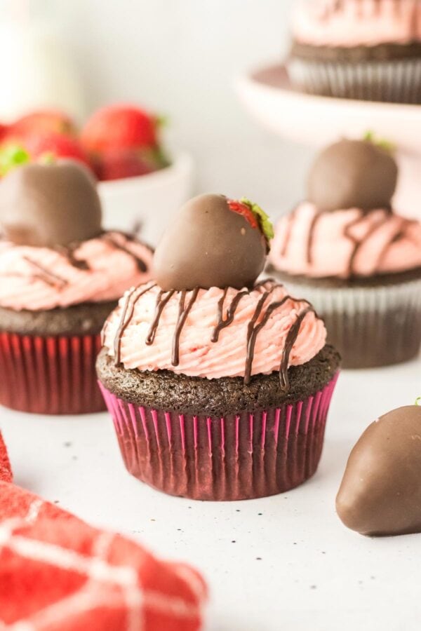 side view of a chocolate cupcake topped with fresh strawberry buttercream and a chocolate drizzle.