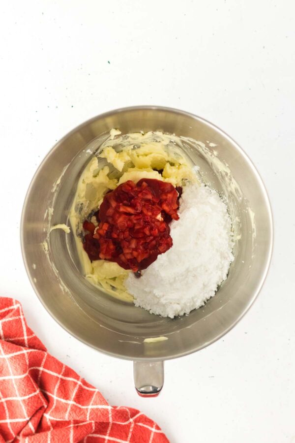 whipped butter with mashed strawberries and powdered sugar in a mixing bowl.