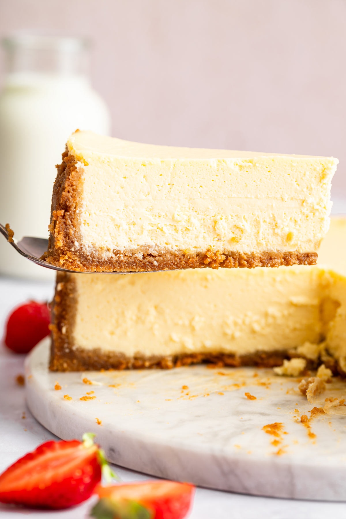 slice of creamy cheesecake being lifted from a whole cheesecake.