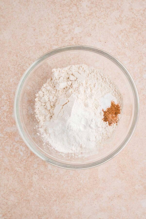 flour, baking powder, baking soda, salt, and spices in a glass mixing bowl.