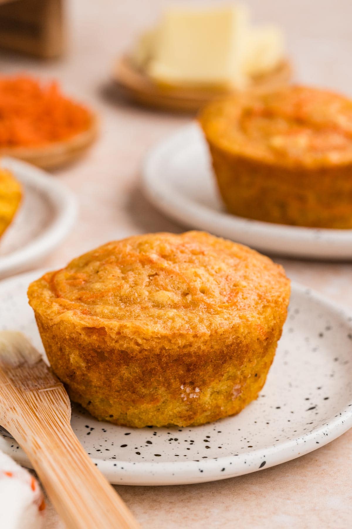 golden brown extra moist carrot muffin on a small dessert plate.