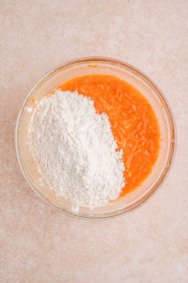 adding dry ingredients to carrot muffin batter.