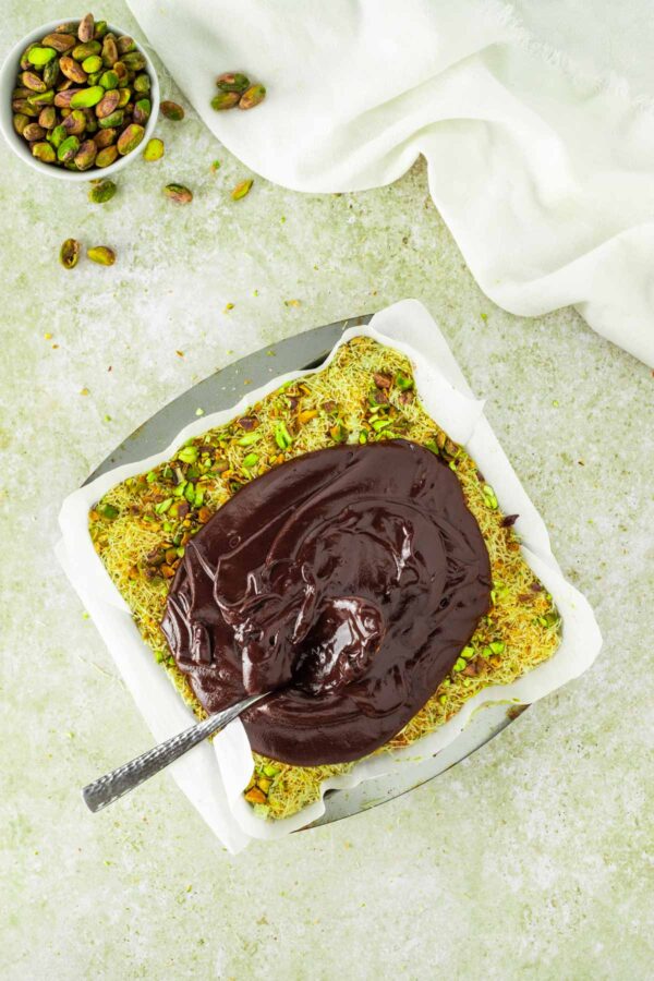 spreading chocolate ganache over dubai chocolate brownies.